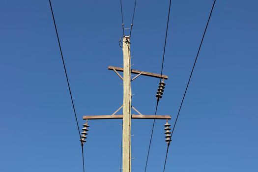 Photograph of a wooden telephone post and cables against a blue sky