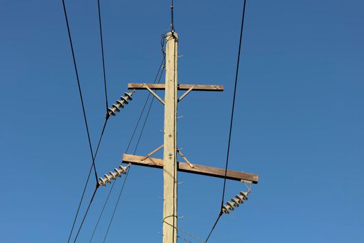 Photograph of a wooden telephone post and cables against a blue sky