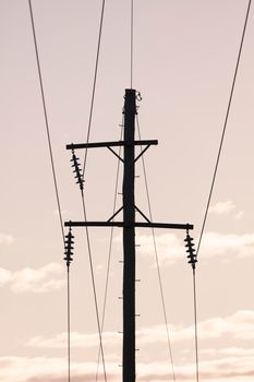 Photograph of a wooden telephone post and cables against a blue sky