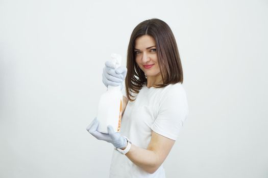 Woman holds spray bottle with antiseptic or detergent like guns. Health or cleaning concept Covid-2019, on white background