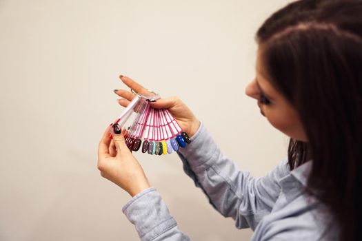 The girl chooses the color of Polish for manicure. Testers nail Polish