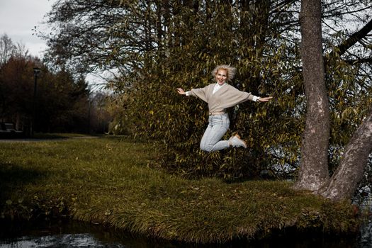 Beautiful woman in park jumping and smiling - sunny day