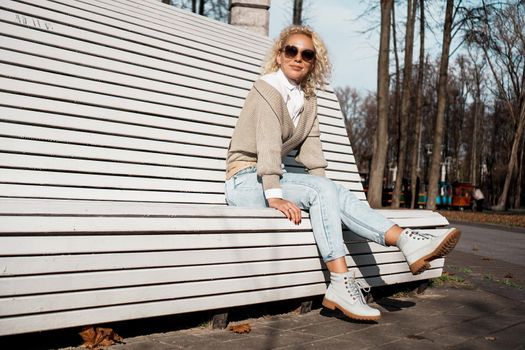 Pretty woman in sunglasses on bench at autumn park alone, lifestyle people concept