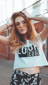 Fashion portrait stylish pretty woman in sunglasses posing in the city, street fashion. You look cool on white t-shirt