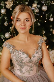 Christmas, winter holidays concept. Beautiful woman in evening long dress posing in luxurious apartments decorated for Christmas. Beauty, fashion.