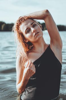 Young beautiful woman standing in the water. Black swimsuit. Vintage style. vertical photo