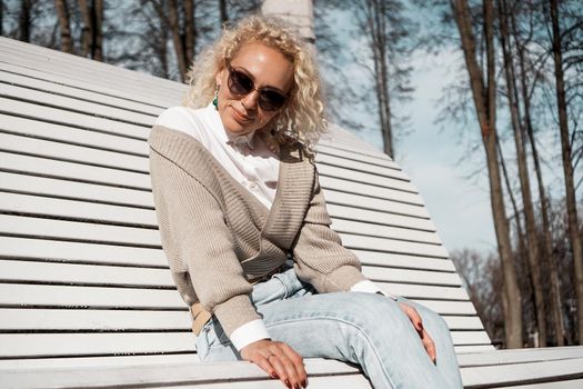 Pretty woman in sunglasses on bench at autumn park alone, lifestyle people concept