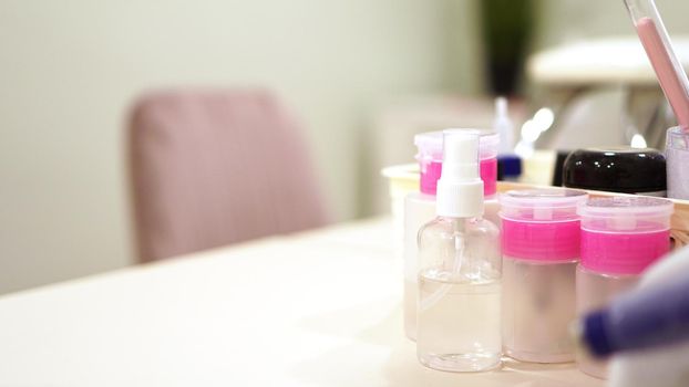 Professional equipment - plastic jars with solutions and water on a blurry background of nail salon. Website banner with place for text
