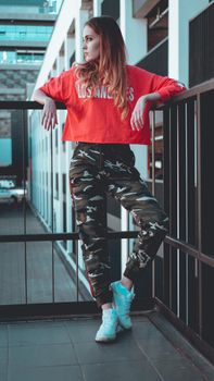 Fashion model wearing red hoodie with the inscription los angeles posing in the city at parking. Fashion urban outfit. Casual everyday clothing style