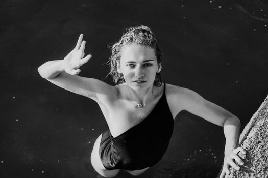 Young beautiful woman standing in the water. Black swimsuit. Vintage style. Black and white