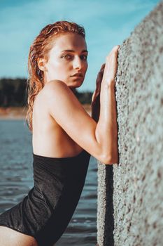 Young beautiful woman standing in the water. Black swimsuit. Vintage style