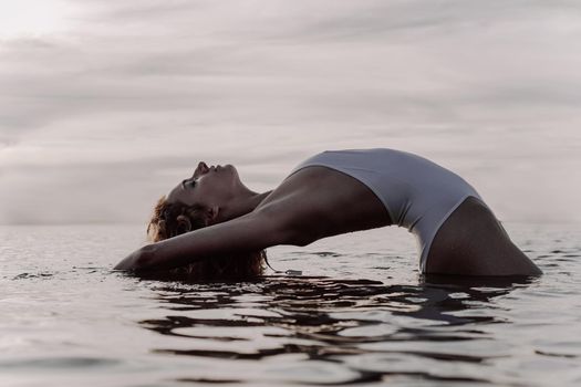 Beautiful sexy woman in a white swimsuit with an open back posing near the lake, photo in vintage style