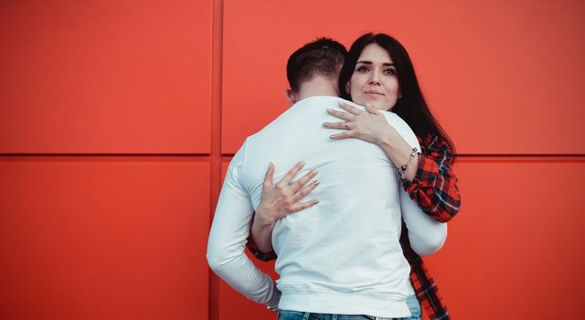 Couple dating and hugging in love in an urban in a sunny day - red background