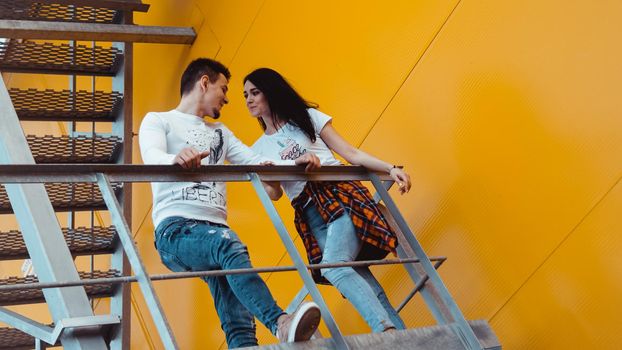 Couple in love on a date holding hands and walking up the stairs - yellow background