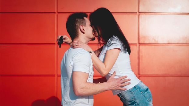 Couple kissing against isolated red wall in the city - red background, love concept