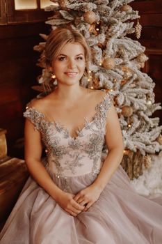 Christmas, winter holidays concept. Beautiful woman in evening long dress posing in luxurious apartments decorated for Christmas. Beauty, fashion.