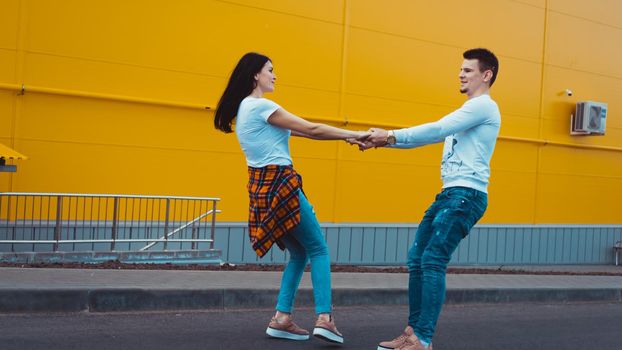 Young smiling couple in love man holding attractive woman hand, spending time together, enjoying - yellow background
