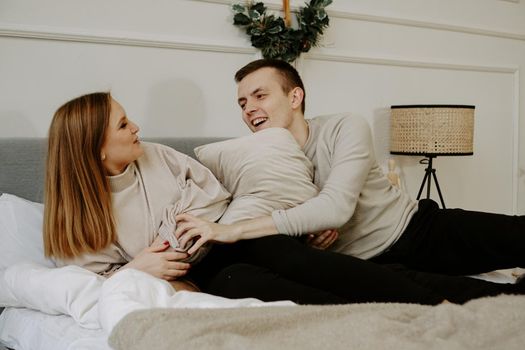 Young happy couple in love is lying in bed, smiling and fooling around. Soft colors