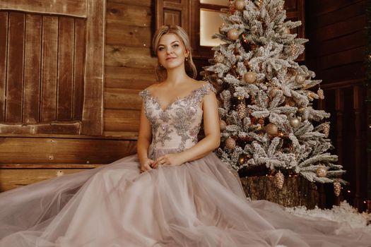 Christmas, winter holidays concept. Beautiful woman in evening long dress posing in luxurious apartments decorated for Christmas. Beauty, fashion.
