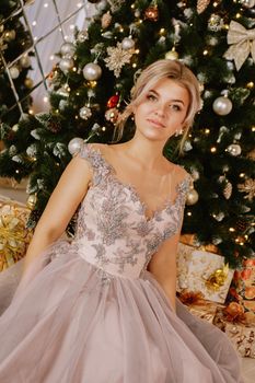 Christmas, winter holidays concept. Beautiful woman in evening long dress posing in luxurious apartments decorated for Christmas. Beauty, fashion.