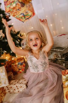 Cute little girl in pink dress with present on background Christmas tree. Merry Christmas and Happy New Year and Holidays