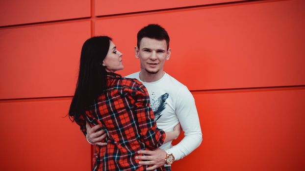 Couple dating and hugging in love in an urban in a sunny day - red background