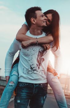 Happy man carrying his girlfriend on sunset background - couple in love
