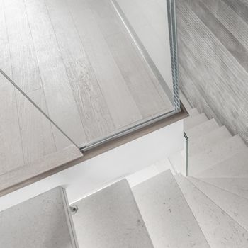 Modern design and innovative material. Microcement stairs with glass handrail. Stairs viewed from above. Glass railing.