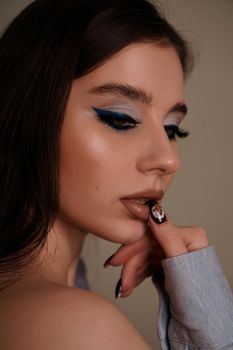 Beauty portrait with professional blue makeup. Fashion portrait of a beautiful brunette woman. Make-up artist, beauty salon, stylist, magazine