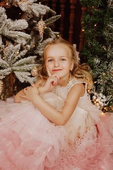Happy Girl in a pink dress near the Christmas tree