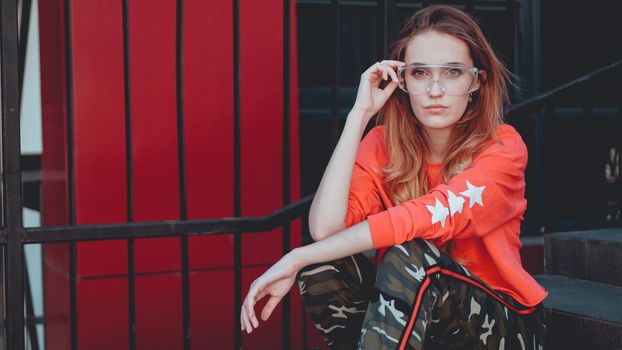 Fashion model wearing red hoodie with the inscription los angeles posing in the city at parking. Fashion urban outfit. Casual everyday clothing style