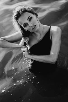 Young beautiful woman standing in the water. Black swimsuit. Vintage style. vertical photo. Black and white