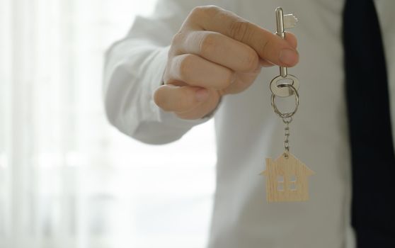 Bank officer or house seller agents giving house key after a successful house purchase agreement.