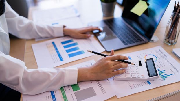 Businesswoman accountant using calculator and laptop for calculating finance and accounting Analyze financial budget in the modern office.