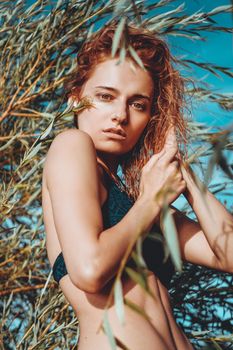 Woman in bikini on a tropical beach with plants - summer time