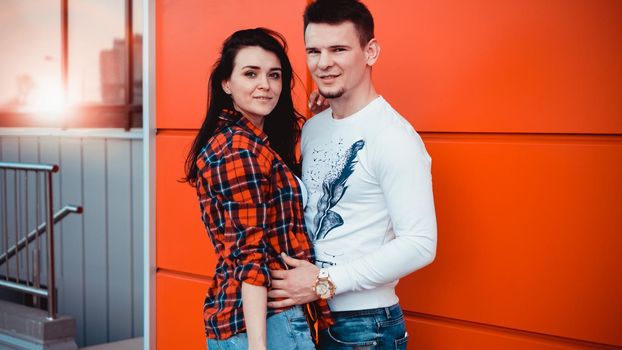Young modern stylish couple urban city outdoors - red background, sunny day, copyspace