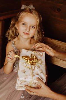 Cute little girl in pink dress with present on background Christmas tree. Merry Christmas and Happy New Year and Holidays