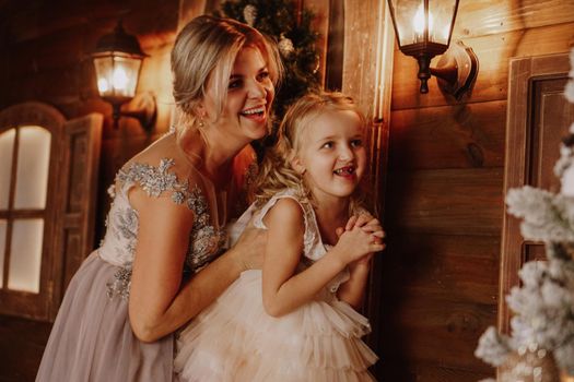 Young beautiful mother holds a little daughter who decorates a Christmas tree in the fairy room