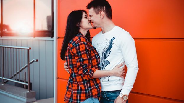 Young modern stylish couple urban city outdoors - red background, sunny day, copyspace