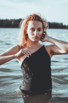 Young beautiful woman standing in the water. Black swimsuit. Vintage style. vertical photo