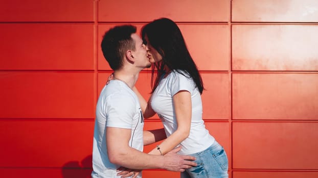 Couple kissing against isolated red wall in the city - red background, love concept