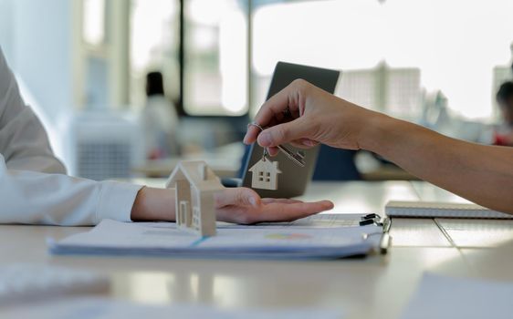 Real estate agents giving house keys to customers after signing contract. The concept for purchasing property or becoming a homeowner.