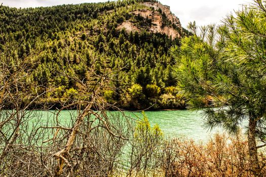 Tolosa reservoir surrounded by vegetation and mountains in Alcala del Jucar village, Albacete, Spain