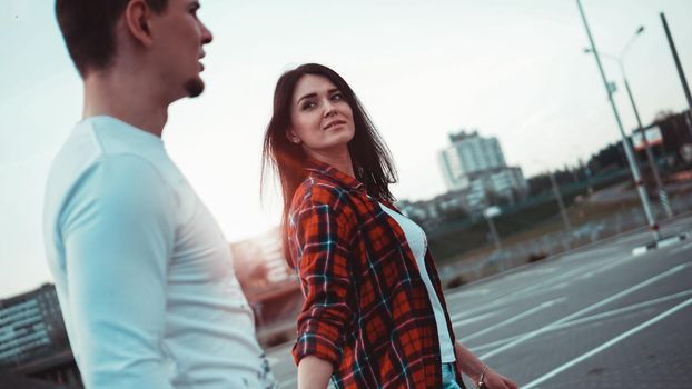 Young Couple holding hands and walking through the city street at sunset