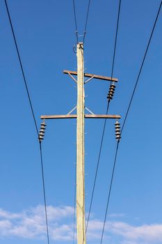 Photograph of a wooden telephone post and cables against a blue sky