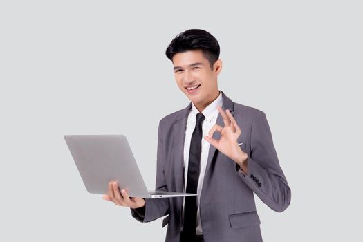 Young asian business man standing work on laptop computer to internet online isolated on white background, businessman confident and notebook, freelance with success, marketing and communication.