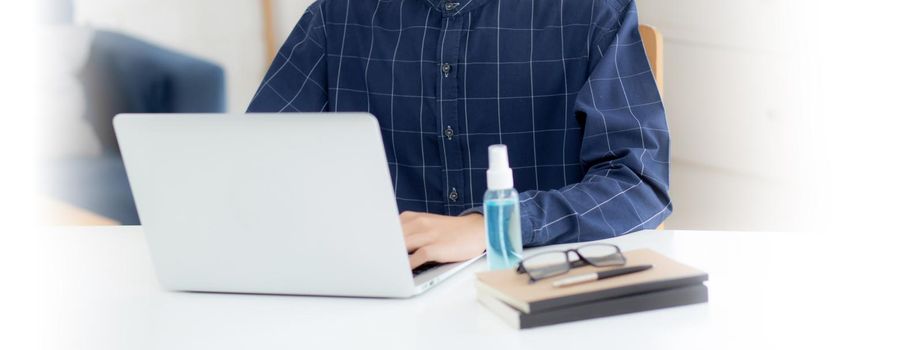 Young business man in face mask working from home with laptop computer on desk for protection for outbreak of covid-19 and healthcare, male quarantine stay home using notebook on desk, new normal.