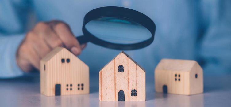 Hand of businessman hold magnifying glass looking house for examining and analyzing quality, inspection and choice home, purchase and search residential and investment, business and property concept.