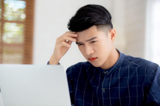 Young asian business man headache during working on laptop computer with deadline on desk at home, businessman with failure exhausted and tired, stress and worried, frustrated and unsuccessful.