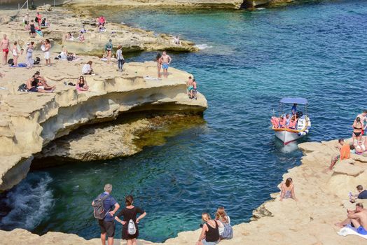 People are enjoying sunny day at Saint Peter's pool near Marsaxlokk, Malta